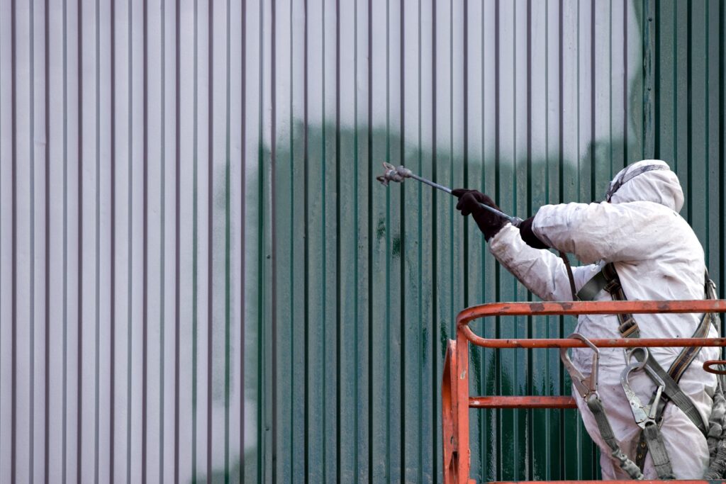 Commercial Painter on an Industrial Lift Spray Painting a Steel Exterior Wall or Duct